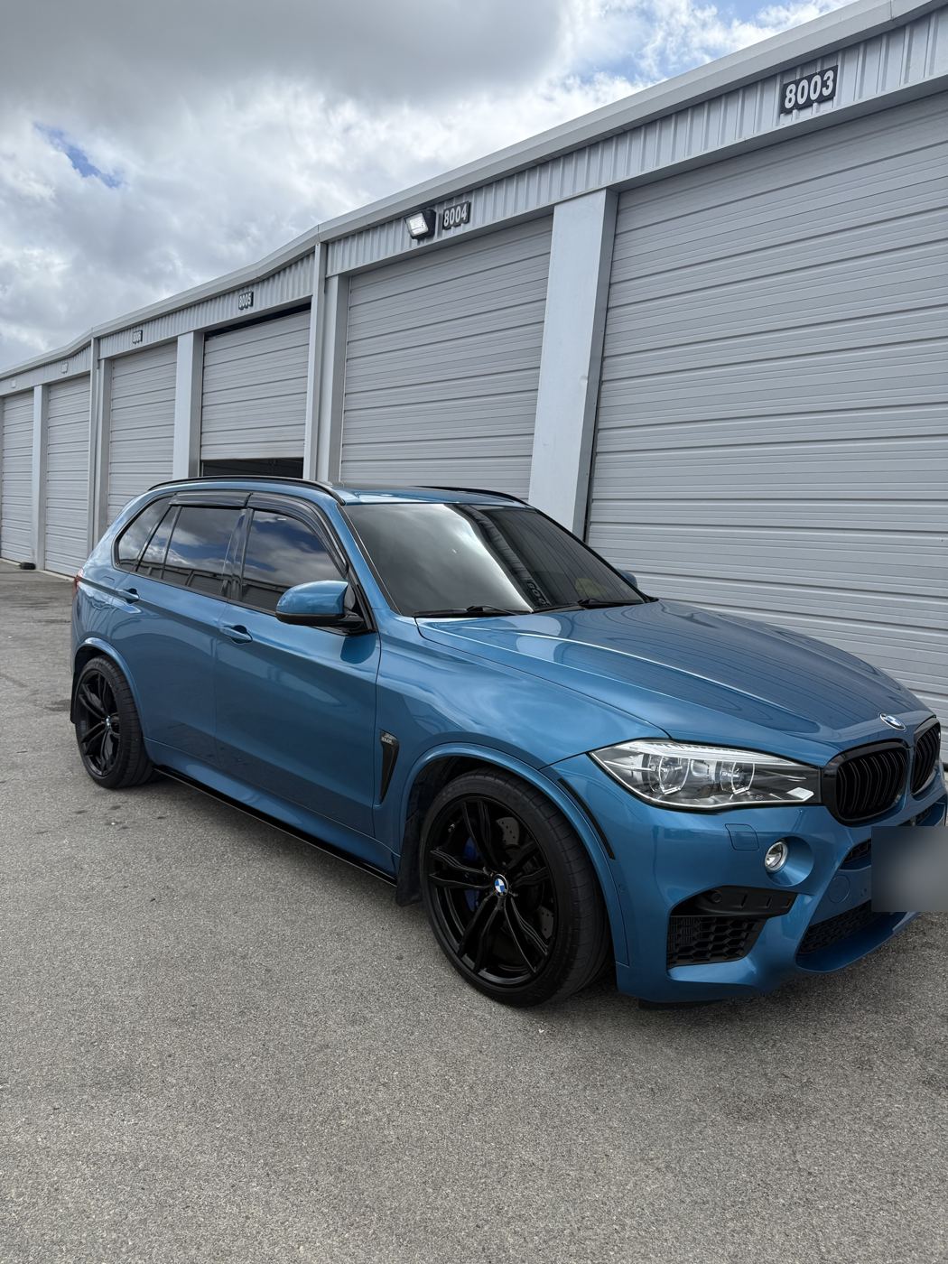 Blue BMW X5 M, side view showing dark tinted side windows